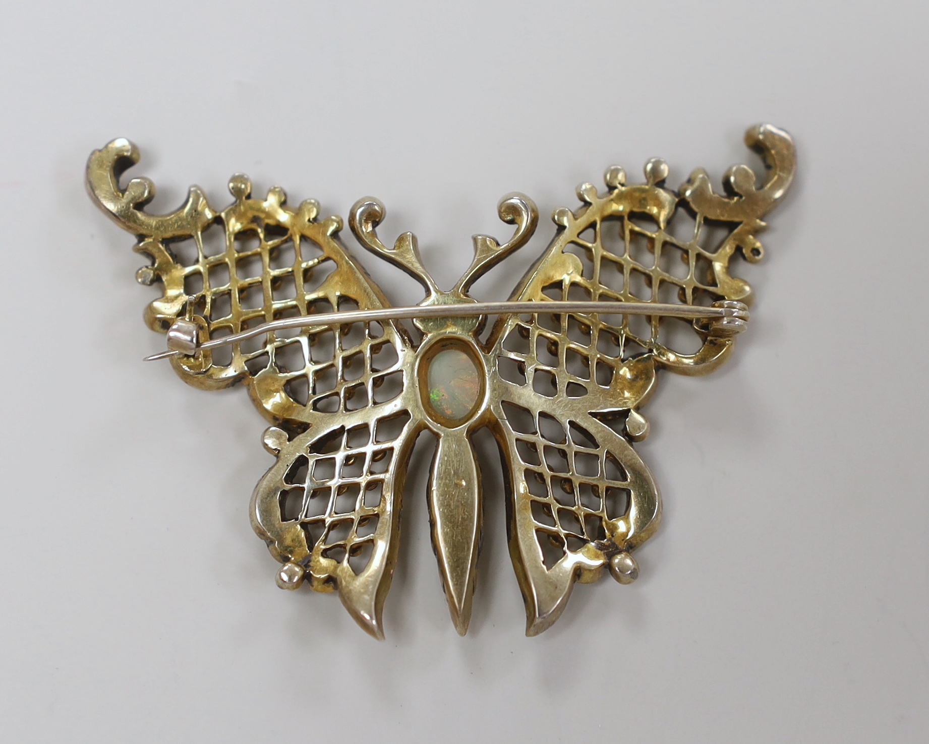 A late 19th/early 20th gilt white metal, white opal and two colour paste set butterfly brooch, width 59mm.